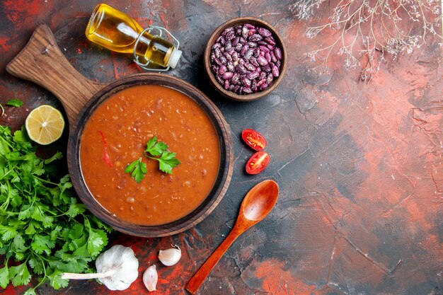 Sopra la vista della zuppa di pomodoro su un tagliere marrone su una tavola di colori misti