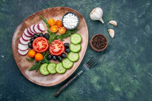 Sopra la vista delle olive fresche delle verdure tritate in un piatto marrone e degli aglio del pepe della forcella sulla tabella di colori misti neri verdi