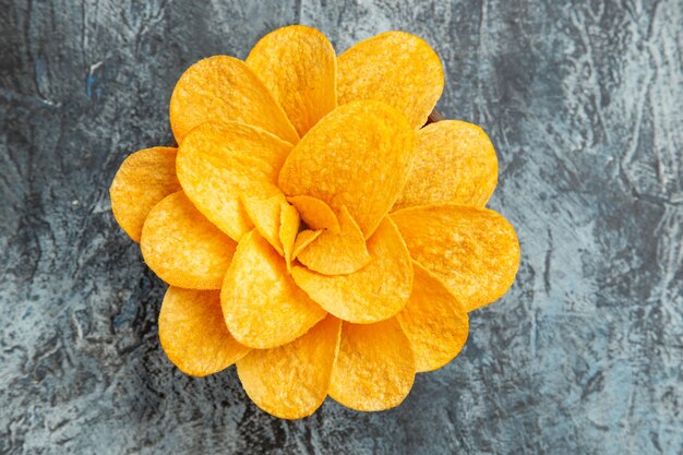 Sopra la vista delle patatine fritte decorate come un fiore a forma di una ciotola marrone sul tavolo grigio