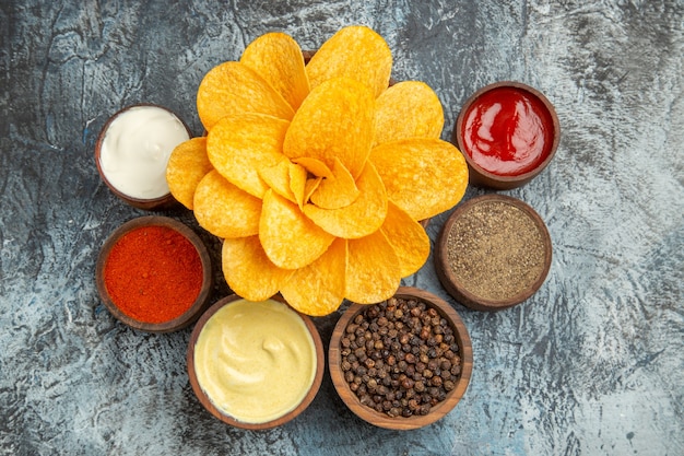 Sopra la vista delle patatine fritte fatte in casa decorate come maionese a forma di fiore e ketchup sul tavolo grigio