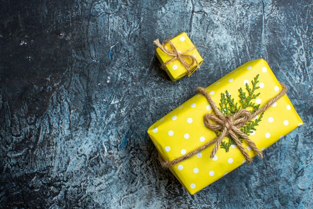 Sopra la vista di bellissime scatole regalo di Natale gialle impilate per i membri della famiglia sul lato sinistro su sfondo scuro