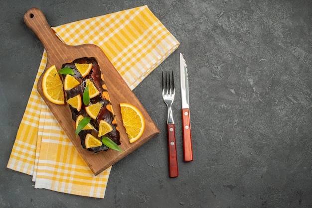 Sopra la vista di deliziose torte morbide su tavola di legno e arance tagliate con foglie sul tavolo scuro