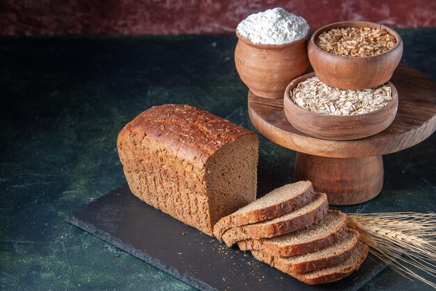 Sopra la vista di fette di pane nero farina di farina d'avena grano saraceno su tavola di colore scuro su fondo invecchiato di colore misto