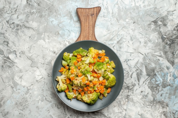 Sopra la vista di insalata di verdure fresca e sana sul tagliere di legno sulla tavola bianca