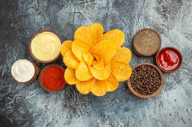 Sopra la vista di patatine fritte con diverse spezie maionese e ketchup sul tavolo grigio