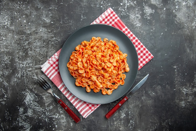 Sopra la vista di un delizioso pasto di pasta su un piatto nero per cena su un panno rosso spogliato