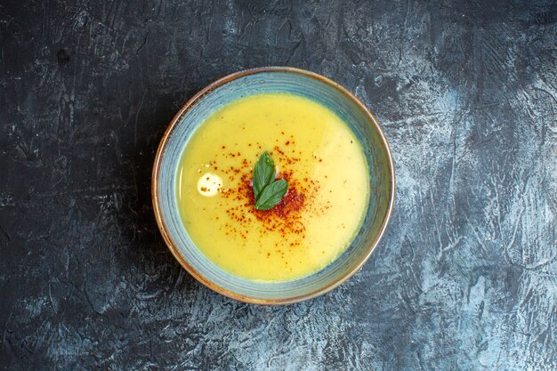 Sopra la vista di una deliziosa zuppa servita con pepe e menta in una pentola blu su sfondo scuro