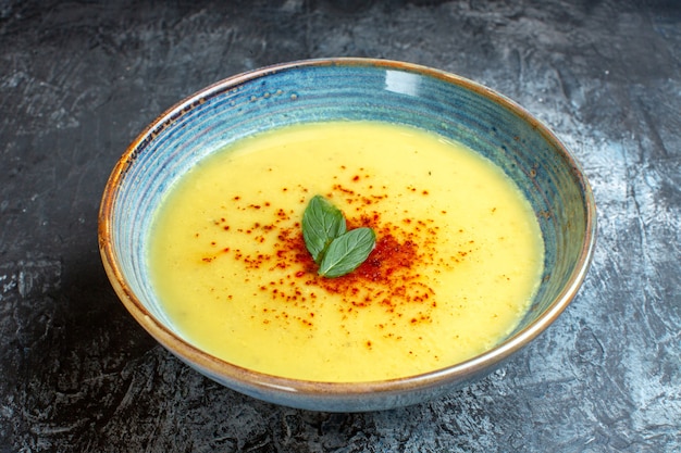 Sopra la vista di una pentola blu con una gustosa zuppa servita con menta sul tavolo blu