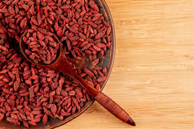 Sopra la vista grande ciotola con bacche di goji e fondo in legno