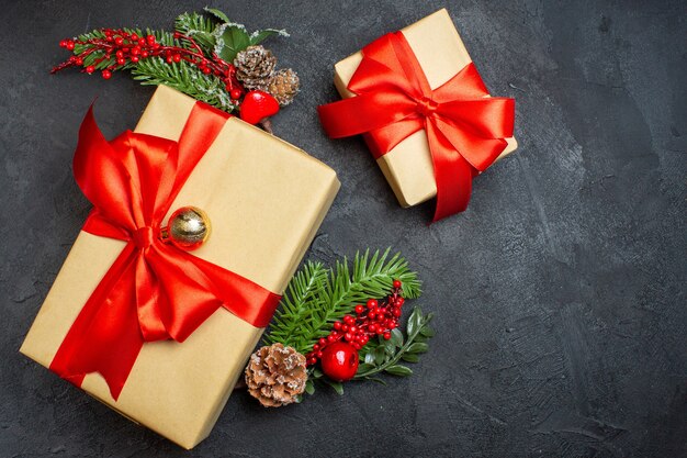 Sopra vista atmosfera natalizia con bellissimi regali con fiocco a forma di fiocco e accessori per la decorazione di rami di abete su uno sfondo scuro