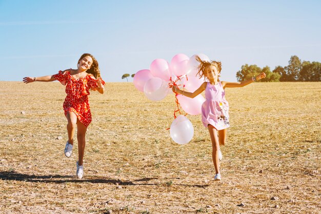 Sorelle che corrono con palloncini