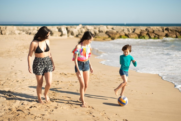 Sorelle felici e fratello che giocano in spiaggia