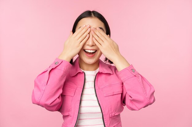 Sorpresa e celebrazione Ritratto di ragazza asiatica felice chiudere gli occhi in attesa di regalo anticipando qualcosa in piedi accecato sullo sfondo dello studio Copia spazio