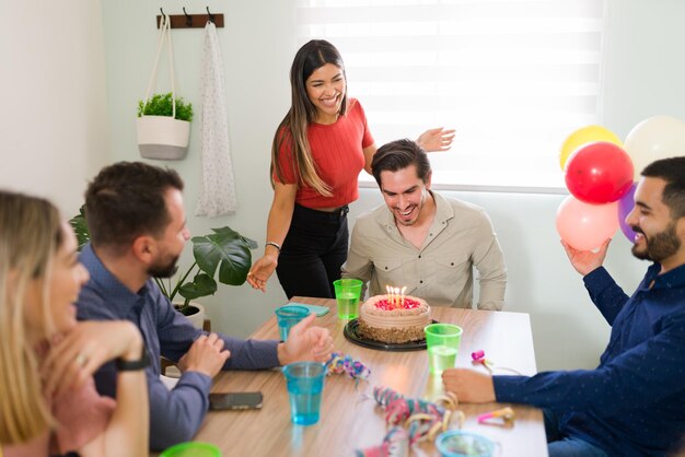 Sorpresa! Giovane bello che si sente grato ed eccitato per la sua festa di compleanno a sorpresa. Gli amici gli augurano un felice compleanno