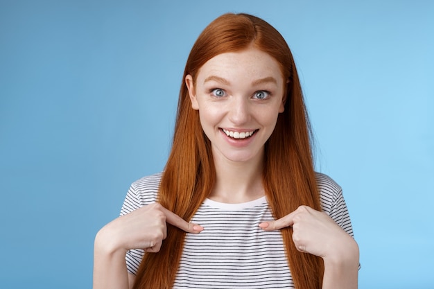 Sorpreso contento impressionato eccitato ragazza rossa occhi azzurri fissa la macchina fotografica affascinato non può credere di vincere indicando se stessa interrogato divertito ottenere nominato primo posto, scelto ricevere borsa di studio.