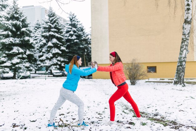 Sorridendo due amici femminili che combattono all&#39;aria aperta nell&#39;inverno