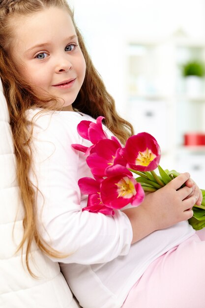 Sorridente bambina in possesso di un mazzo di fiori