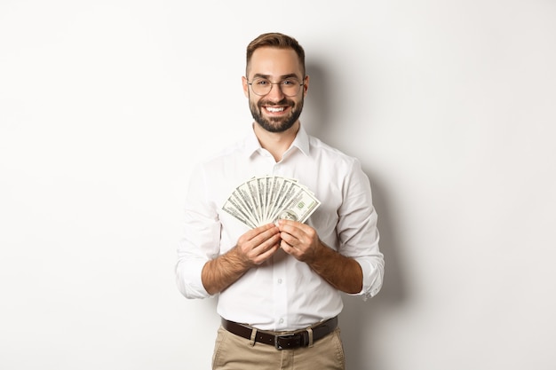 Sorridente bell'uomo in possesso di denaro, mostrando dollari, in piedi