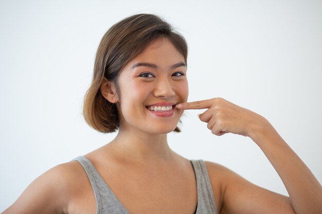 Sorridente bella donna asiatica che punta ai suoi denti