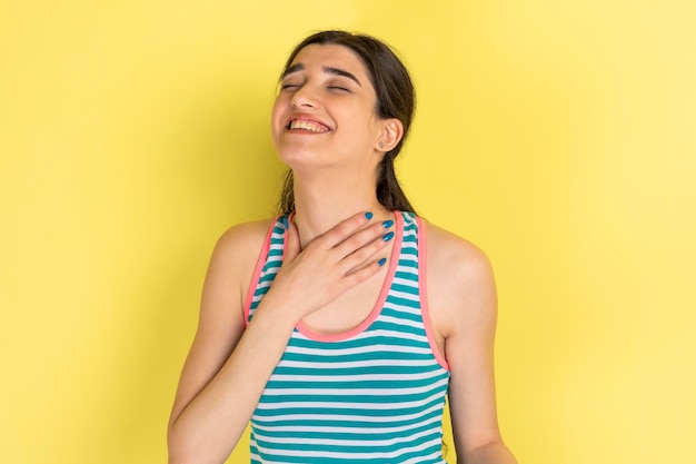 Sorridente bella ragazza chiuse gli occhi e si mette la mano al collo Foto di alta qualità