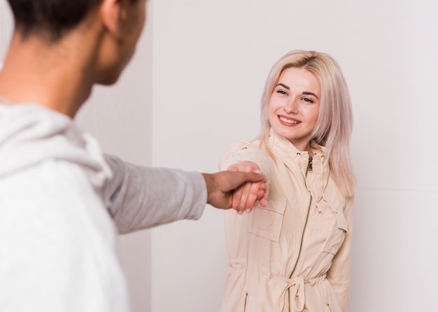 Sorridente bionda giovane donna tenendo la mano del suo fidanzato