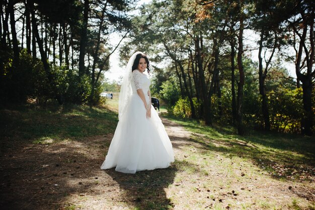 Sorridente bruna sposa in piedi all&#39;aperto