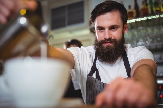 Sorridente cameriere fare tazza di caffè al banco