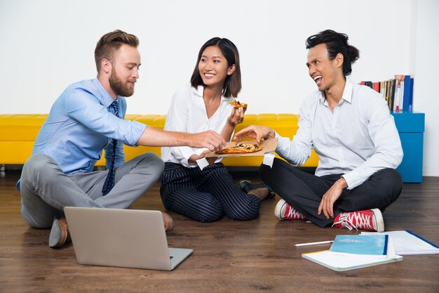 Sorridente colleghi di lavoro mangiare la pizza a pranzo