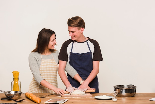 Sorridente coppia di rotolare la pasta insieme