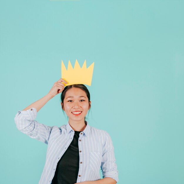 Sorridente donna asiatica con corona di carta