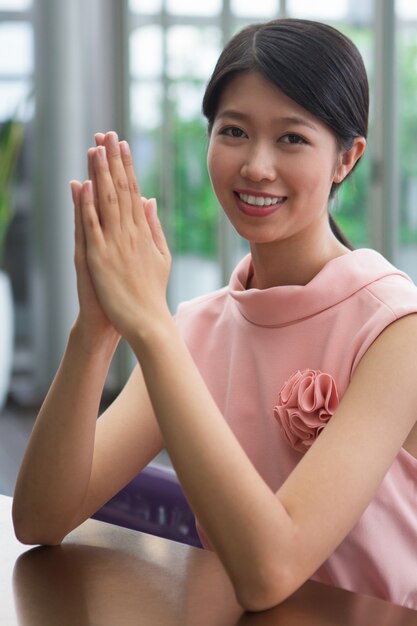 Sorridente donna asiatica con le mani premuti insieme