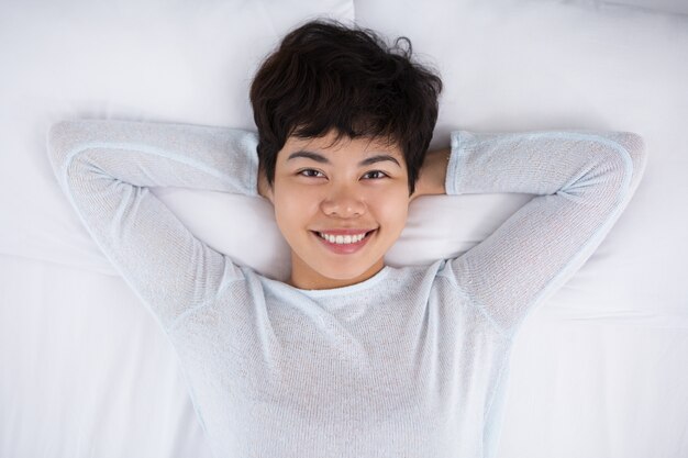 Sorridente donna asiatica piuttosto che riposa nel letto