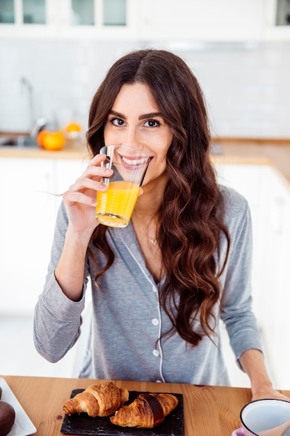 Sorridente donna che beve il succo per la colazione