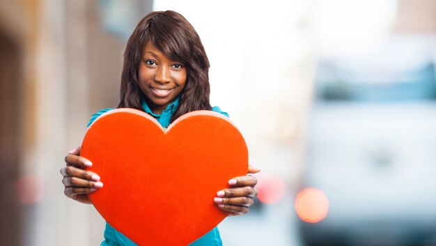 Sorridente donna con un cuore rosso in mano