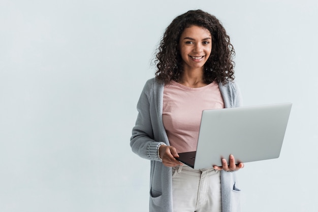 Sorridente donna etnica con computer portatile grigio