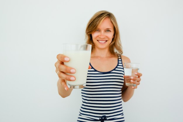 Sorridente donna graziosa che offre bicchiere di latte