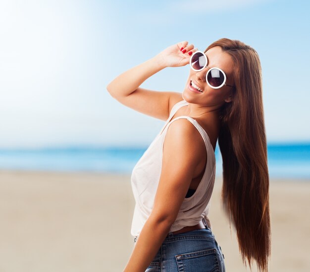 Sorridente donna in occhiali da sole sulla spiaggia