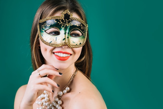 Sorridente donna in topless che indossa mascherata maschera di carnevale e collana