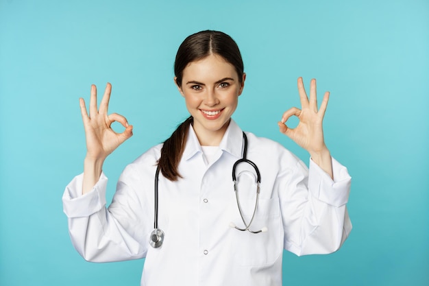 Sorridente donna medico professionista medico lavoratore mostrando ok ok firmare approvazione raccomandando clini...