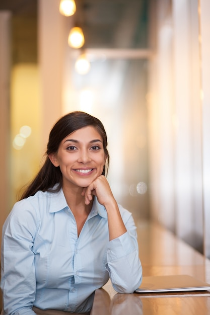 Sorridente Donna seduta in caffè con il computer portatile chiuso