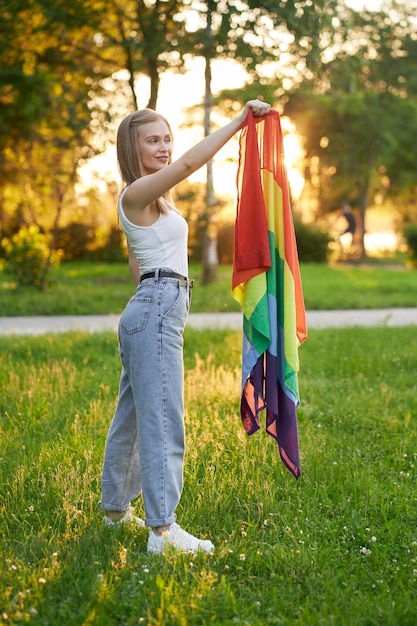 Sorridente donna tollerante che tiene bandiera arcobaleno lgbt