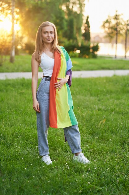 Sorridente donna tollerante che tiene bandiera arcobaleno lgbt