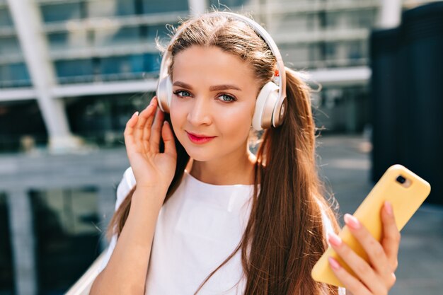 Sorridente e danza giovane donna che tiene uno smartphone e ascolta musica in cuffia