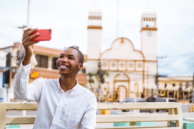 Sorridente giovane afroamericano che si fa un selfie con una moschea dietro