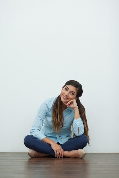 Sorridente giovane bella donna seduta sul pavimento