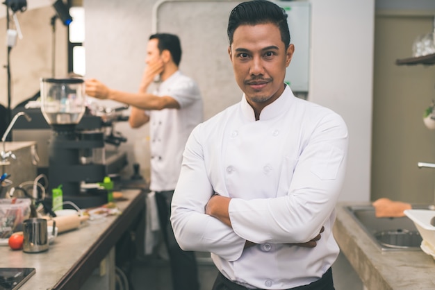 Sorridente giovane chef asiatico in cucina interiore.