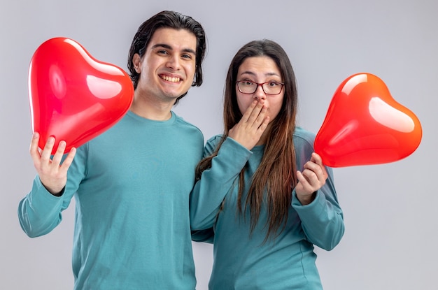 Sorridente giovane coppia il giorno di San Valentino tenendo palloncini cuore isolati su sfondo bianco white