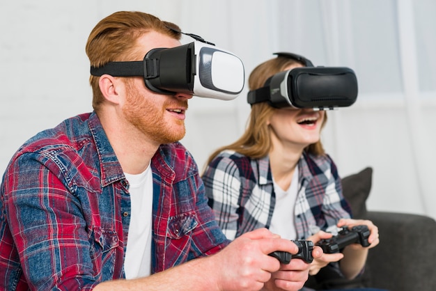 Sorridente giovane coppia indossando occhiali di realtà godendo la riproduzione del videogioco