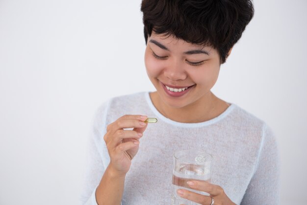 Sorridente giovane donna abbastanza asiatica prendere pillola