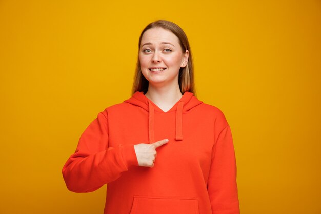 Sorridente giovane donna bionda che punta a se stessa